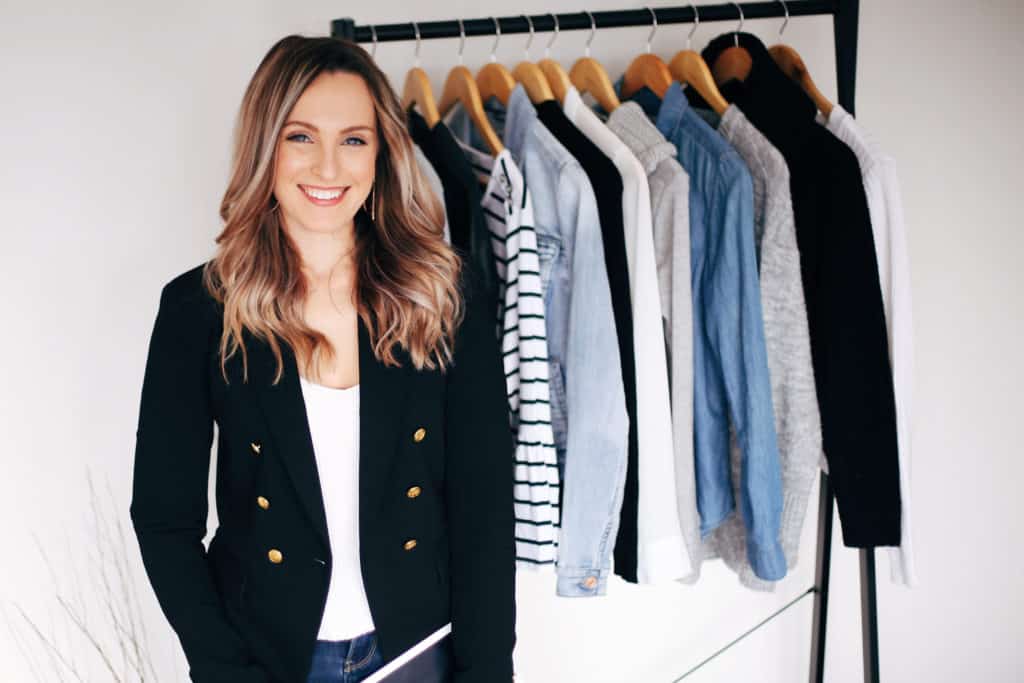 Hayley Cooper poses and smiles in front of a clothing rack.