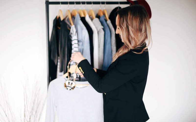 Hayley Cooper hangs clothing on a rack. Hayley Cooper hangs clothing on a rack.